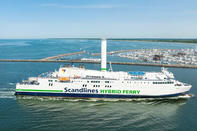 Eine Scandlines Hybridfähre fährt in der Nähe eines Hafens auf offenem Wasser.