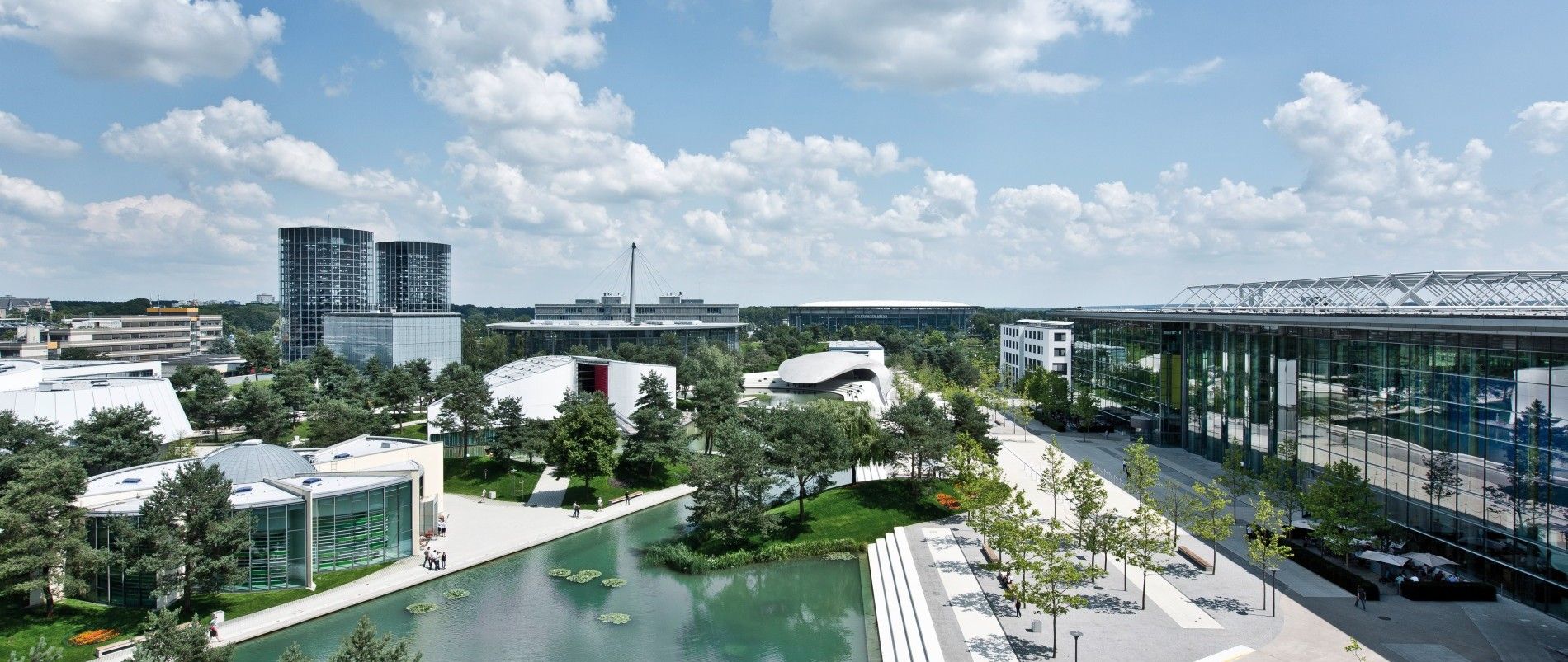 Moderne Gebäude mit Glasfassaden und grüner Landschaft bei sonnigem Wetter