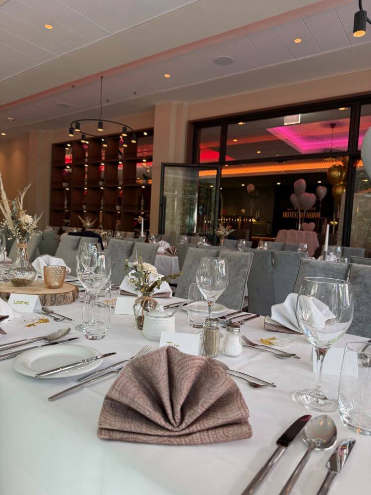 Modern eingerichtetes Restaurant mit lila Beleuchtung und gedeckten Tischen.