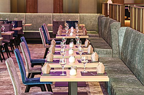 Elegant gedeckte Tische in einem stilvollen Restaurant mit Weingläsern und gefalteten Servietten.