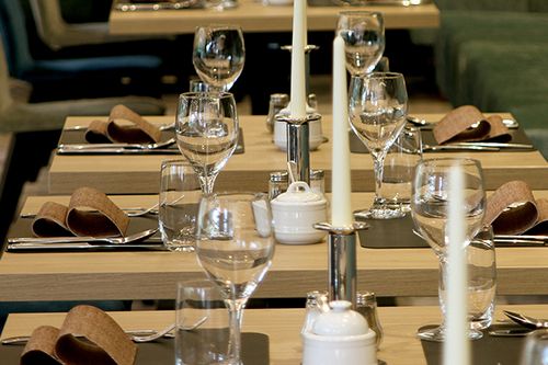 Elegantly gedeckter Tisch in einem Restaurant, mit Weingläsern, Kerzen und Stoffservietten.