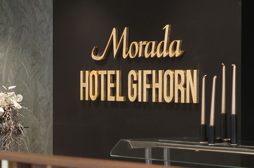 Eingangsbereich des Morada Hotel Gifhorn mit einer dekorativen Blumenarrangement und modernen Kerzenhaltern.