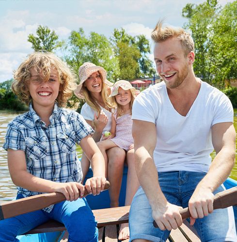 Eine fröhliche Familie genießt einen Sommertag beim Rudern auf einem See.